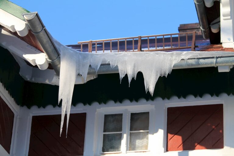 Long icicles hanging from a snow-covered roof edge