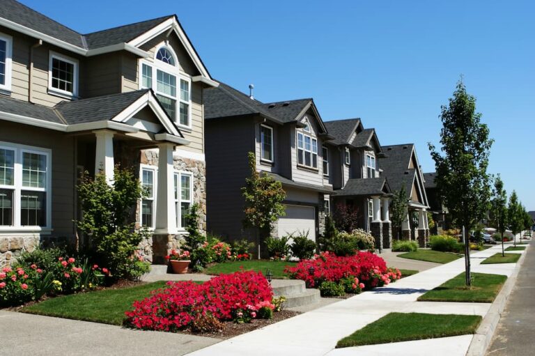 Row of two-story homes with shingle roofs along a tree-lined sidewalk