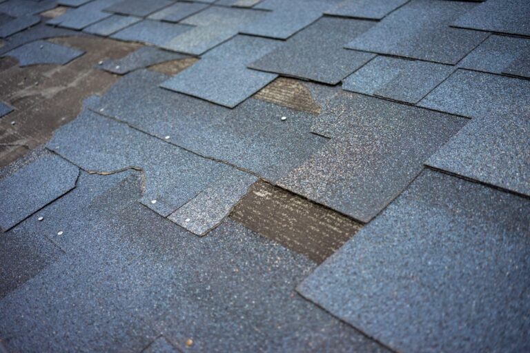 Worn asphalt shingles with missing granules and lifted tabs