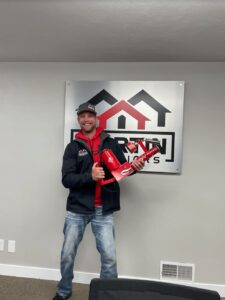 Martin Exteriors team member holding an award in front of the company logo