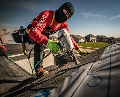 Roofer nailing new architectural shingles on a roof replacement | Martin Exteriors