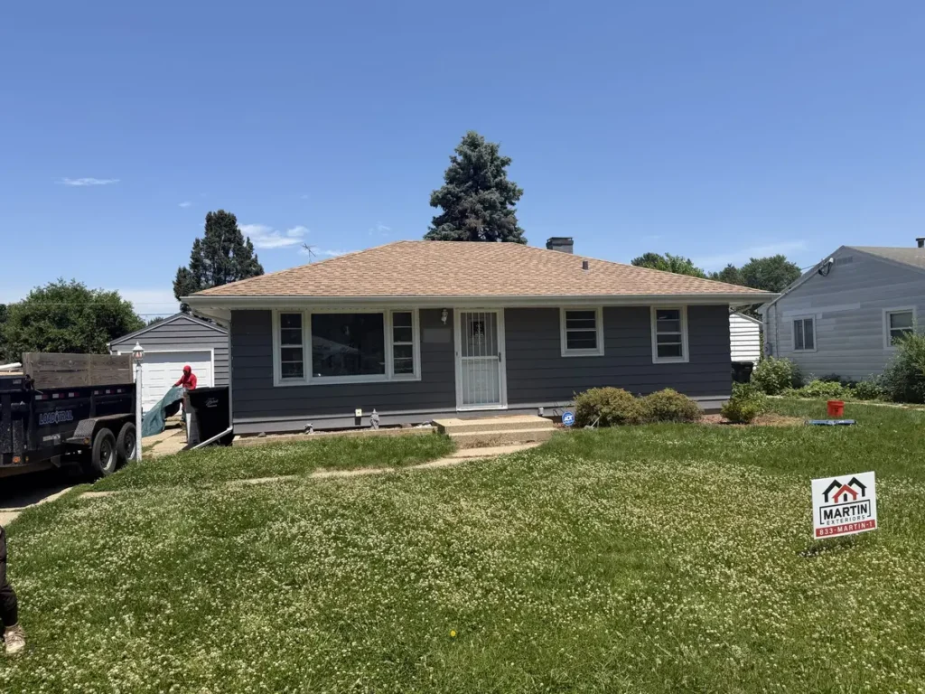 Tan and brown shingle roof on a one story home with dark gray siding in Beloit, WI