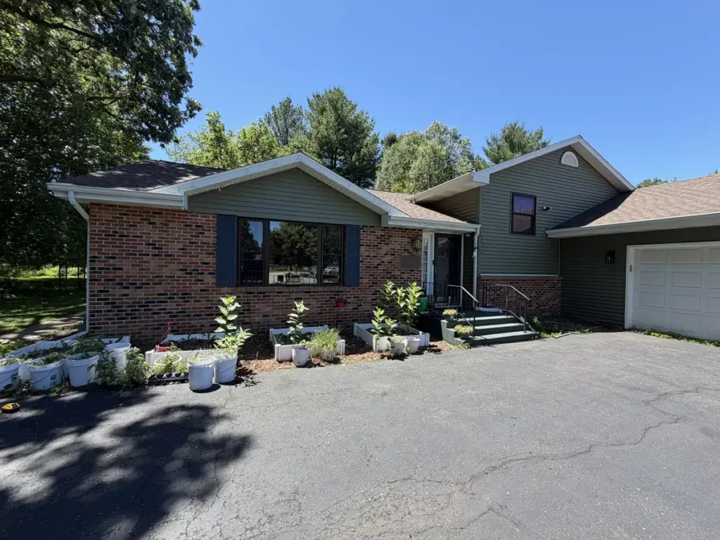 Beloit, WI home with green vinyl siding, red brown brick and dark shutters