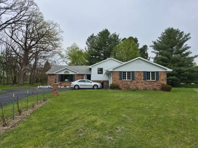 Beloit, WI home with white siding and a gray shingle roof before the roof and siding replacement