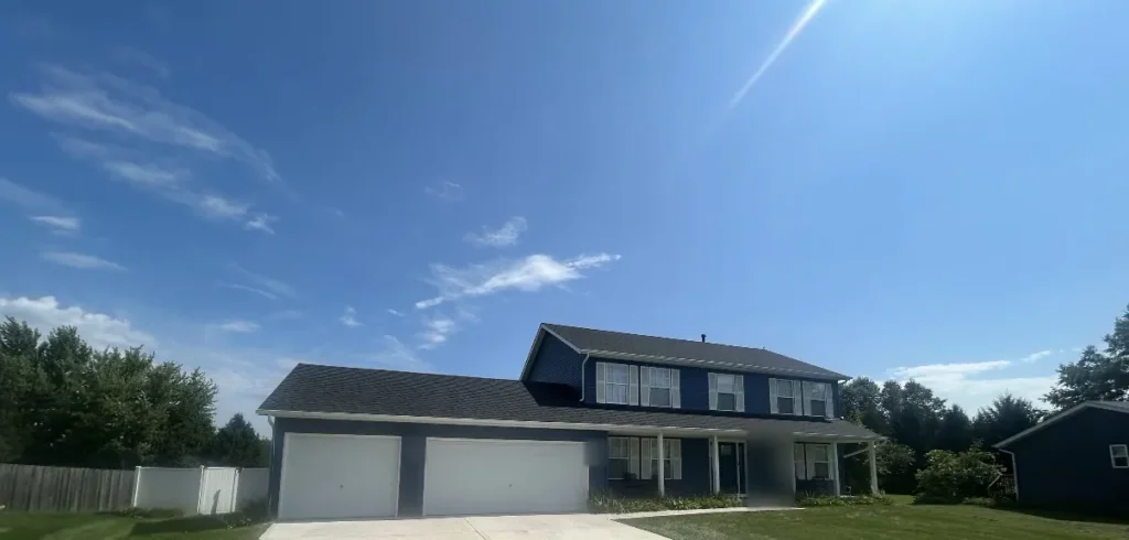 Wide view of a two story Durand, IL house in dark blue vinyl siding with an attached garage