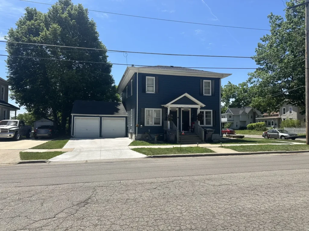 Two story Janesville, WI home with deep blue vinyl siding, white trim and a detached garage