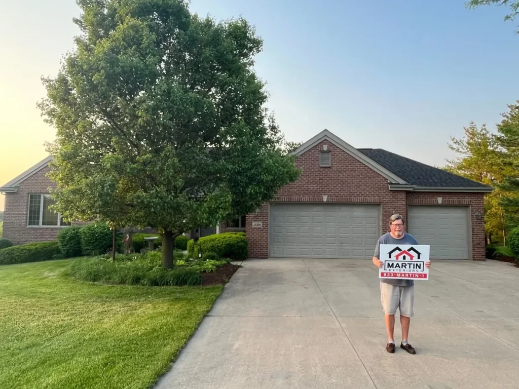 Martin Exteriors Roofing & Siding customer holding a yard sign in front of a brick home