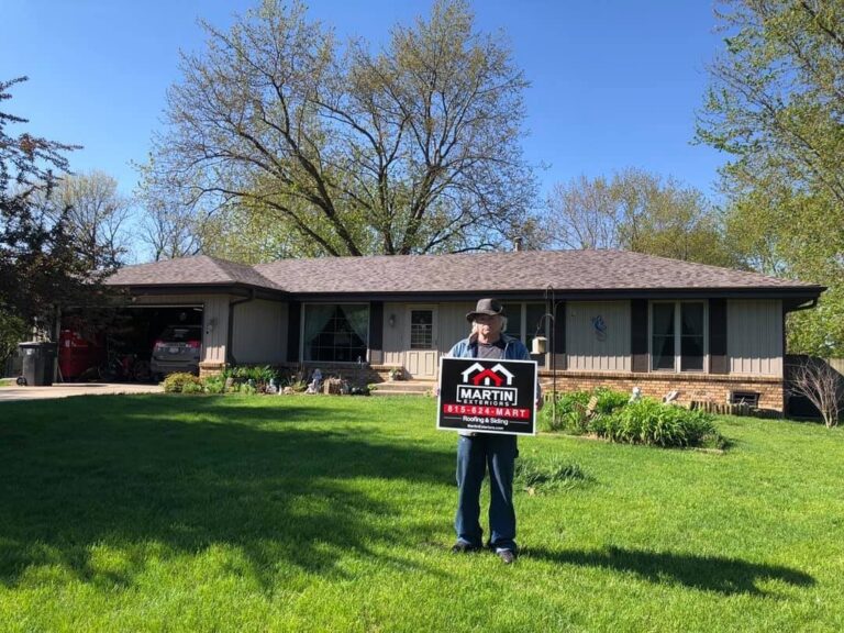 Martin Exteriors project in Rockford, IL: homeowner holding a Martin sign in front of a ranch home with a brown shingle roof