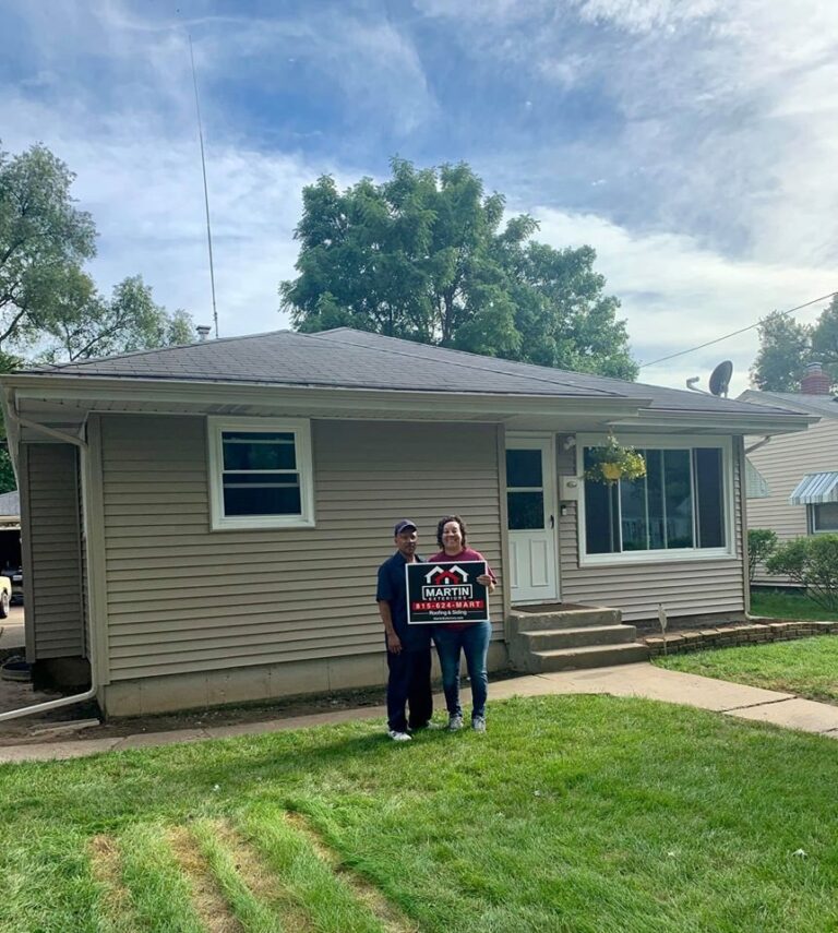 Martin Exteriors project in Rockford, IL: two homeowners holding a Martin sign in front of a ranch home with tan vinyl siding