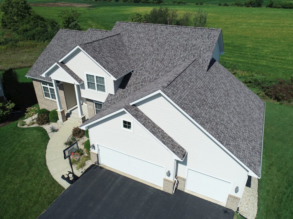Aerial view of a gray shingle roof by Martin Exteriors on a two-story home with a three-car garage