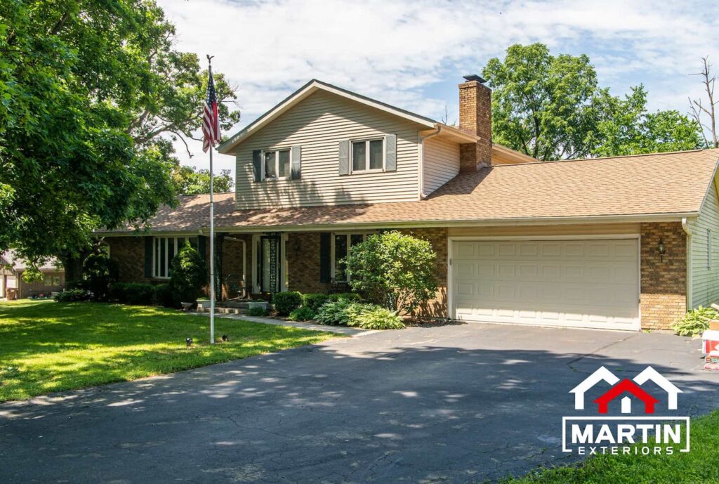 Tan shingle roof by Martin Exteriors on a two-story brick and siding home with a chimney