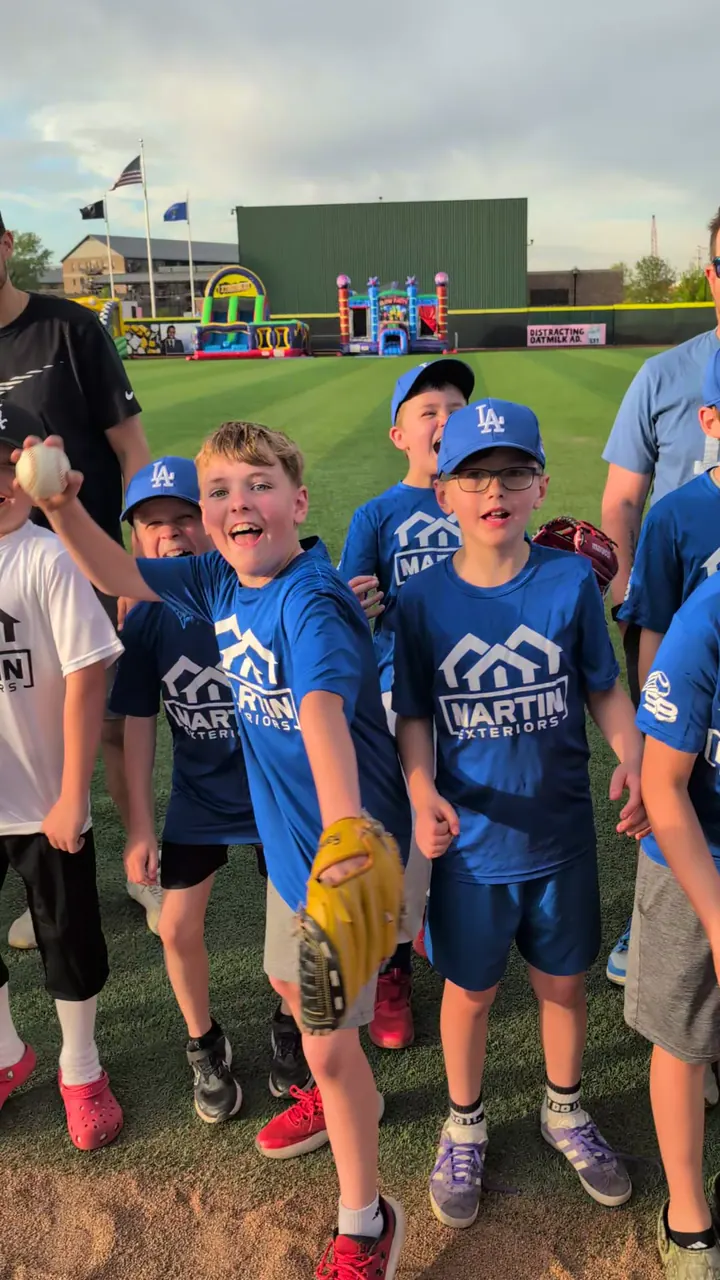 Young Stateline Baseball players in blue Martin Exteriors shirts cheering on the field